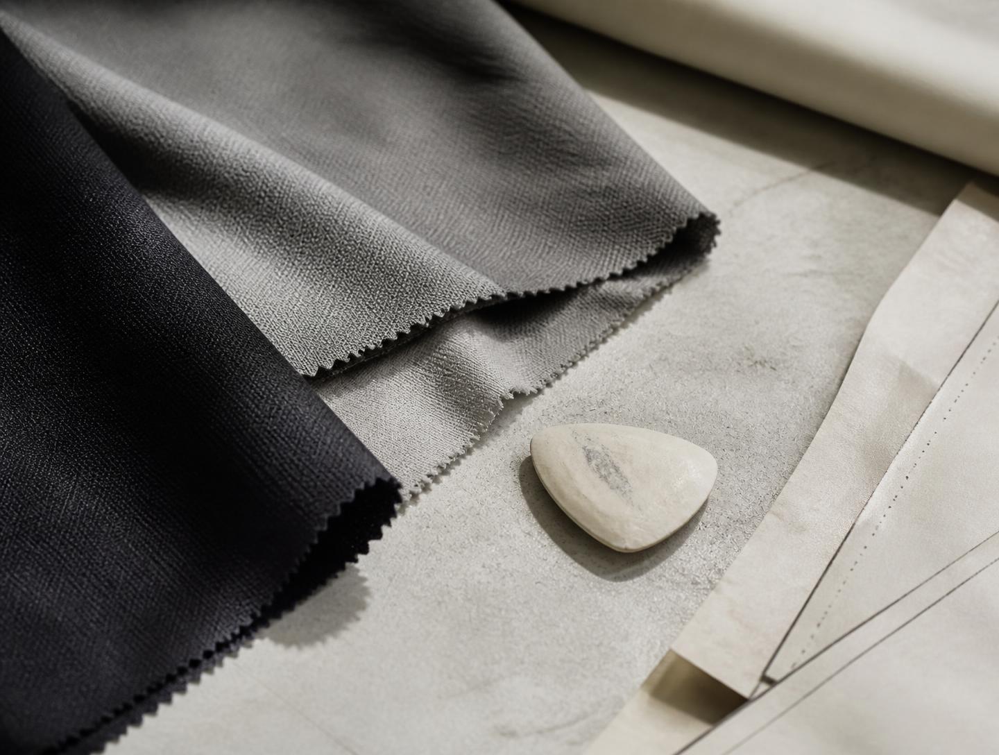 Fabric swatches, pattern paper and tailoring tools on a studio table